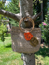 Load image into Gallery viewer, Crocheted bag with floral embellishments hanging on a tree branch