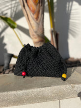 Load image into Gallery viewer, Black knitted pouch with colorful drawstrings on a stone surface