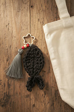 Load image into Gallery viewer, Dark gray knitted fish-shaped keychain with tassel on a light gray background