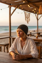 Load image into Gallery viewer, blond woman with short hair at the beach wearing a black and gold patterned crochet mesh hat