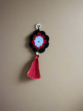 Load image into Gallery viewer, Crocheted keychain with a red tassel on a beige background