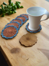 Load image into Gallery viewer, Set of crocheted coasters on a wooden surface with a white mug.