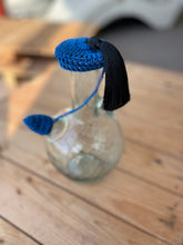 Load image into Gallery viewer, Blue and black knitted tassels on a clear glass bottle with a blurred background