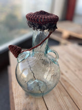 Load image into Gallery viewer, Glass bottle with a textured brown top on a wooden surface