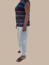 Load image into Gallery viewer, Person wearing a colorful dress and white pants on a tiled floor.