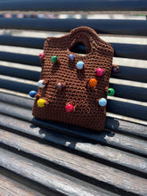 Load image into Gallery viewer, Brown knitted bag with colorful beads on a metal bench