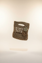 Load image into Gallery viewer, Woven handbag with decorative flower detail against a natural background