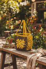 Load image into Gallery viewer, Crocheted bag with yellow and brown pattern on a bench