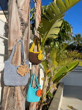 Load image into Gallery viewer, Three handbags hanging on a wooden post with plants in the background