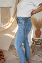Load image into Gallery viewer, Person wearing blue jeans and a white shirt sitting on a white surface.