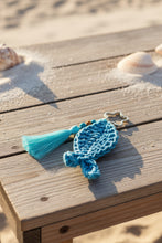 Load image into Gallery viewer, Blue knitted fish-shaped keychain with a tassel on a gray background