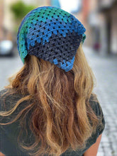 Load image into Gallery viewer, Person wearing a blue and green crocheted headband with blurred outdoor background