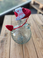 Load image into Gallery viewer, Glass jar with a red and white crocheted heart on a wooden surface