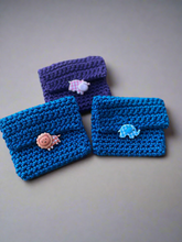 Load image into Gallery viewer, Three blue purple crocheted pouches with animal-themed buttons on a wooden surface