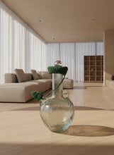 Load image into Gallery viewer, Small glass bottle with green lid and decorative elements on a light gray background