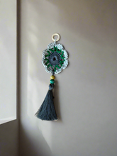Load image into Gallery viewer, Decorative wall hanging with a crocheted design and tassel on a plain background