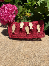 Load image into Gallery viewer, Red woven pouch with fish patterns on a textured surface with pink flowers.