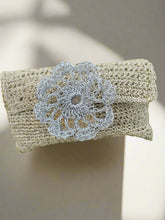 Load image into Gallery viewer, Beige clutch bag with a silver floral brooch on green foliage