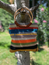 Load image into Gallery viewer, Crocheted bag with a wooden handle hanging on a tree branch