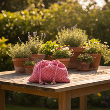 Load image into Gallery viewer, Pink knitted hat with a green bead on a concrete surface