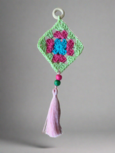 Load image into Gallery viewer, Crocheted square with flowers and tassel on a gray background