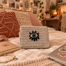 Load image into Gallery viewer, Knitted pouch with an evil eye design on a wooden surface