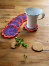 Load image into Gallery viewer, Set of colorful crocheted coasters on a wooden surface with a white mug.