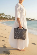 Load image into Gallery viewer, Person holding a textured handbag outdoors with greenery in the background