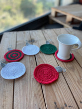 Load image into Gallery viewer, Set of colorful crocheted coasters on a wooden surface with a cup for Christmas