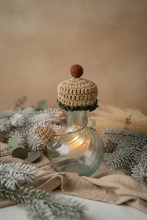 Load image into Gallery viewer, A handmade crocheted hat with a brown pom-pom and a matching brown scarf, styled on a clear glass bottle against a light gray tiled background.