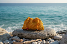 Load image into Gallery viewer, Yellow knitted pouch with red and brown buttons on a concrete surface