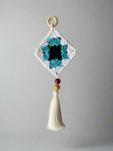 Load image into Gallery viewer, Crocheted diamond-shaped ornament with tassel on a gray background