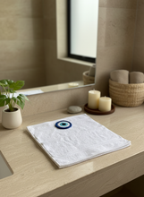 Load image into Gallery viewer, White towel with evil eye design in bathroom setting