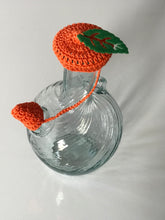 Load image into Gallery viewer, Green leaf on an orange crocheted water jug lid