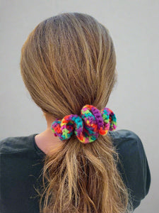 Colorful scrunchie in a person's hair with a blurred outdoor background