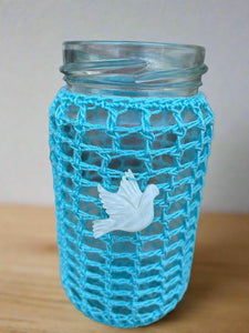 Glass jar with a blue net cover and white dove ornament on a neutral background