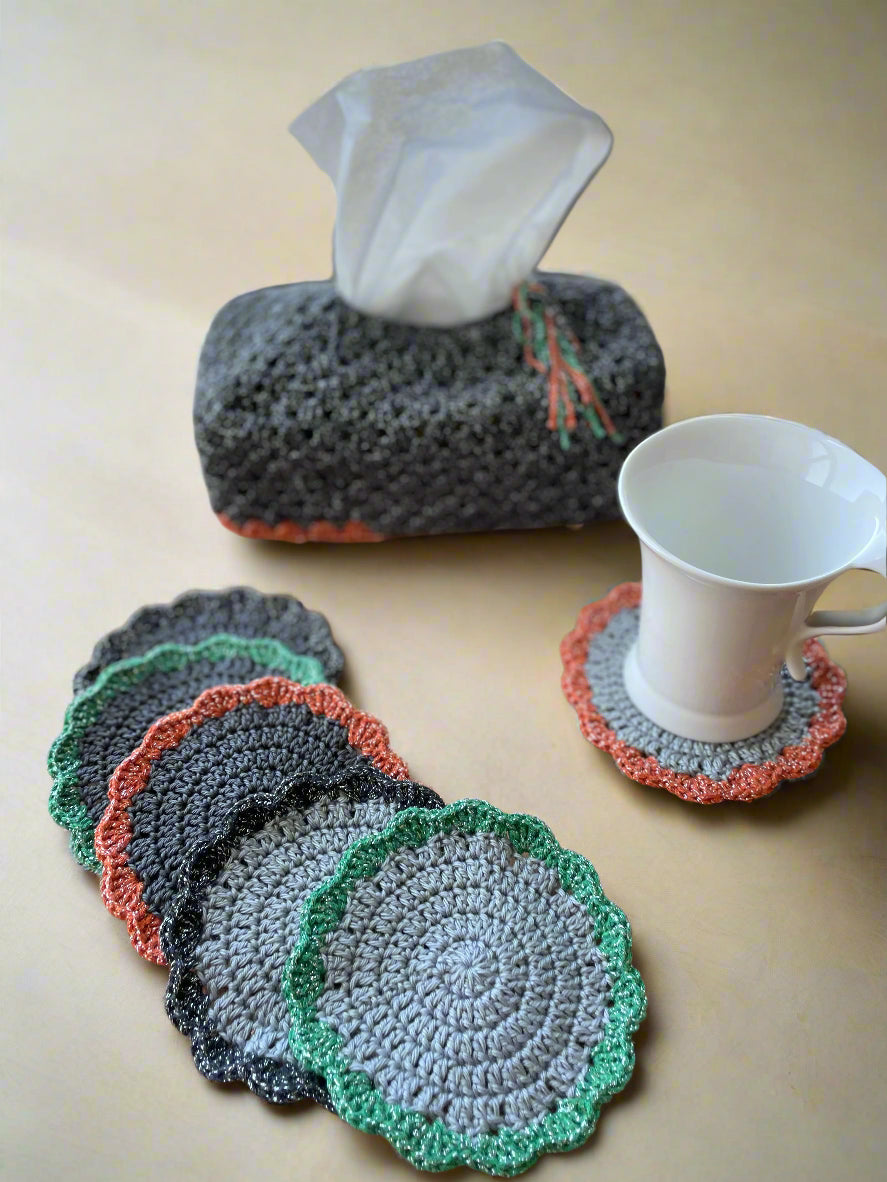 Set of crocheted coasters on a wooden surface with a tissue box and cup.