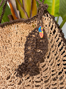 Close-up of a woven bag with a colorful tag against a natural background