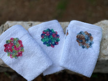 Load image into Gallery viewer, Three white embroidered towels with floral patterns on a stone surface.
