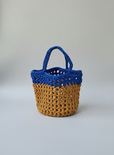 Load image into Gallery viewer, Two-toned blue and brown crocheted bag on a textured surface
