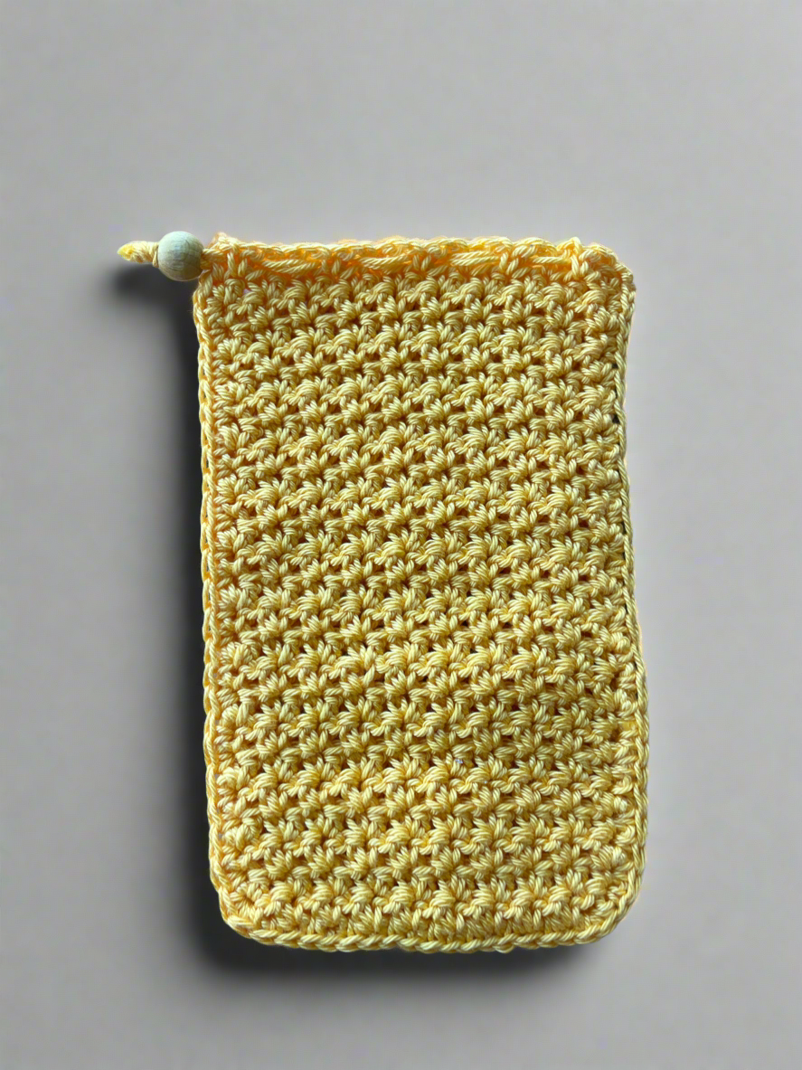 Yellow knitted pouch with a green button on a gray background