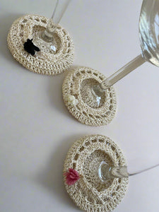 Three crocheted wine glass coasters on a textured surface