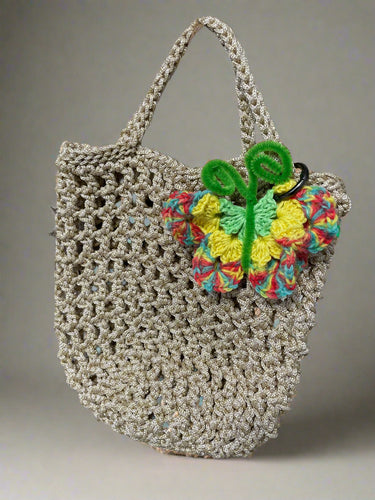 Crocheted bag with a colorful  butterfly decoration on a natural background