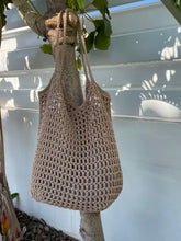 Load image into Gallery viewer, Knitted bag hanging on a tree branch with a white wall in the background
