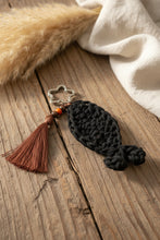Load image into Gallery viewer, Black knitted keychain with a star-shaped keyring and brown tassel on a gray surface
