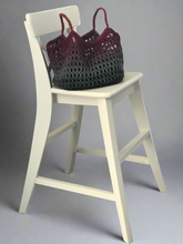 Load image into Gallery viewer, Crocheted bag on a white stool against a gray background
