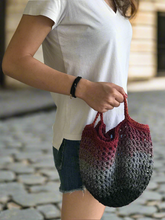 Load image into Gallery viewer, Person holding a gradient handbag on a stone pavement
