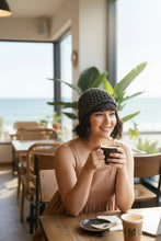 Load image into Gallery viewer, woman in a coffee shop holding a coffee and wearing a black and silver crochet beanie 
