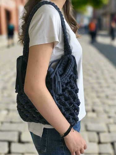 Person wearing a navy blue knitted bag on a blurred street background