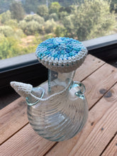 Load image into Gallery viewer, Water jug with a blue and white crochet cover 
